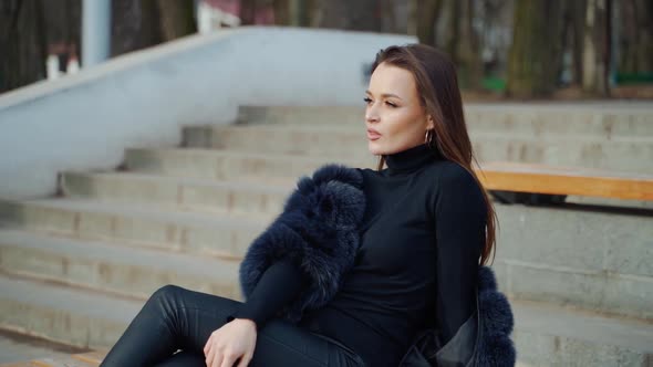 Sexy brunette woman posing wearing dark fur coat looking to tha camera