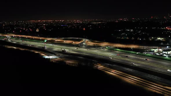 Top down night city roads with cars driving aerial view. Nightly urban cityscape with modern skyscra