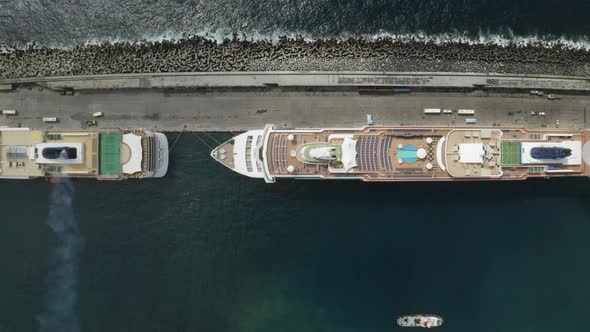 Top down cinematic pan left of aerial view of cruise ships docked in port in the city of Ponta Delga