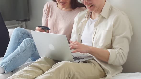 Young Married Couple Sits at Home at a Laptop and Makes Online Purchases Via the Internet a Man