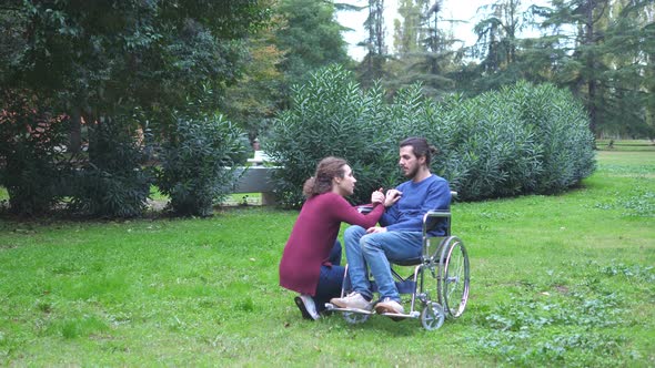 woman kneeling near her boyfriend using wheelchair comforts him