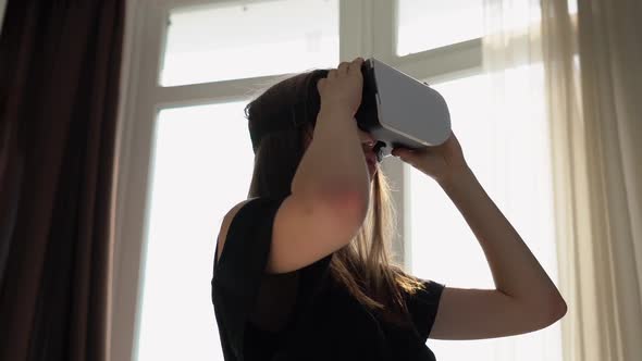 Girl Carefully Looks at Something in VR Glasses