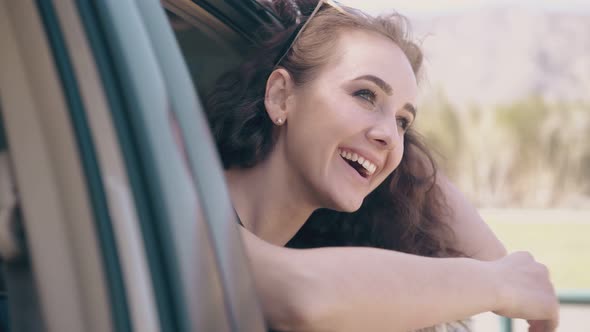 Girl with Loose Hair Laughs in Car Against Blurred Field