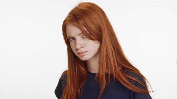 Outraged Redhaired Caucasian Teenage Girl Standing on White Background Looking at Camera and Away