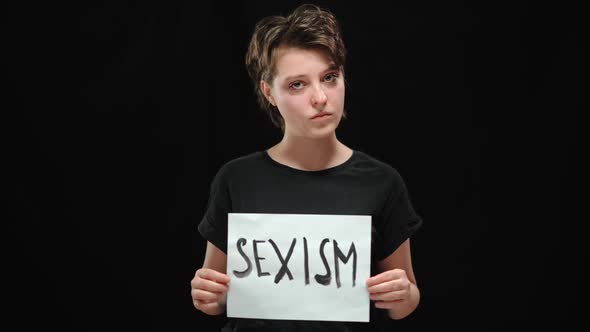 Portrait of Angry Young Brunette Woman Shaking Head No and Tearing Sexism Sign Looking at Camera