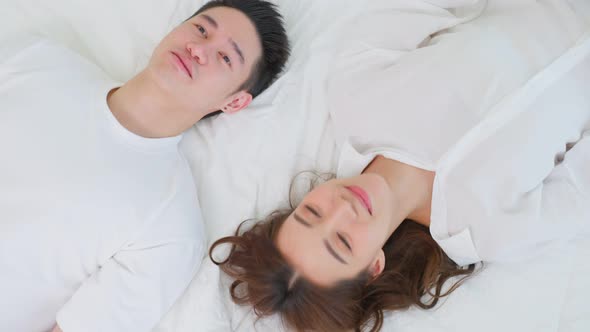 Portrait of Asian new marriage couple lying on bed and look each other.