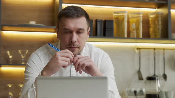 Man Watches Educational Video in Laptop Turning Pen in Hands