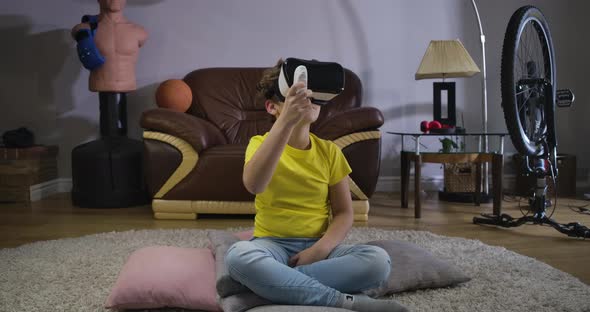 Male Caucasian Teen Wearing VR Headset Using Remote Control To Play the Game. Child Looking Around