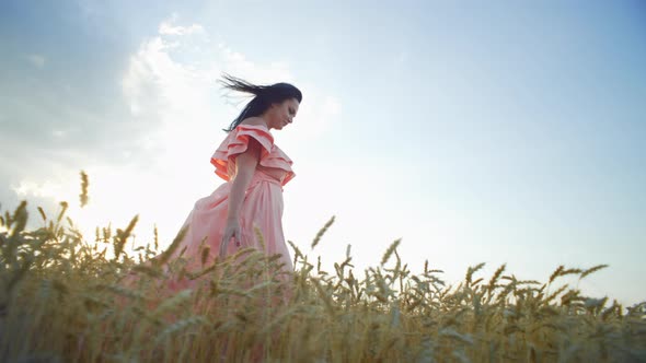 A Beautiful Girl in a Dress Walks Through a Golden Wheat Field