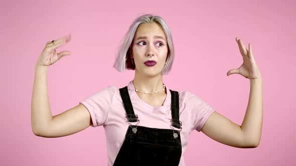 Cute Girl with Dyed Hair Showing Bla-bla-bla Gesture with Hands and Rolling Eyes Isolated on Pink