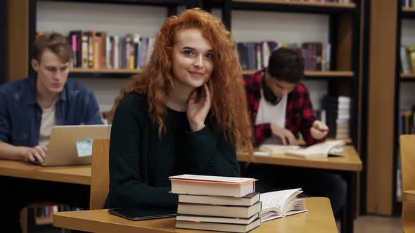 Portrait of a Young Red Headed Curly Female Student Working on Her Thesis or Preparing for Exam