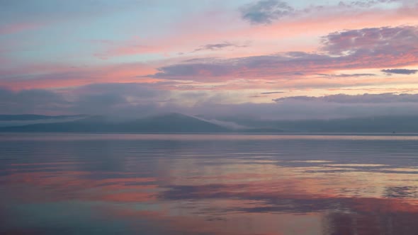 Stunning Panoramic View of Bay Against Horizon with Sunset and Orange Sky Under Dense Moving Clouds