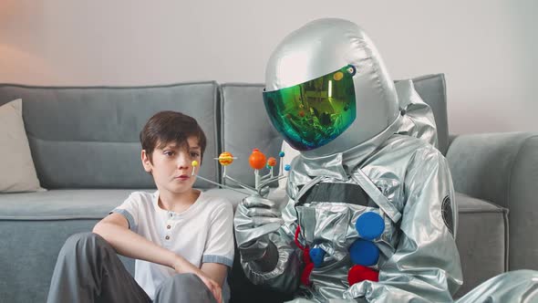 Father and Son Play in the Living Room at Home Father in an Astronaut Costume Sitting on the Floor