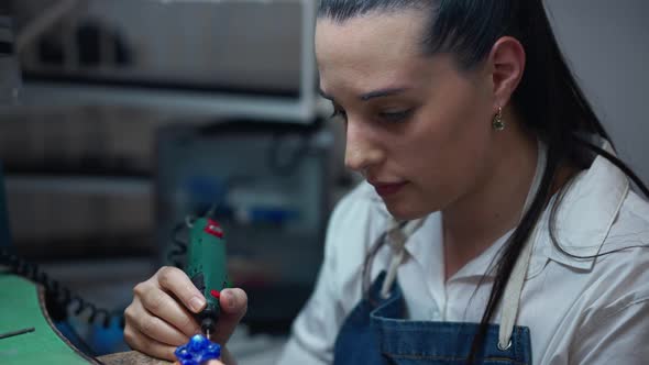 Young Concentrated Female Jeweller Working with Equipment in Workshop Indoors