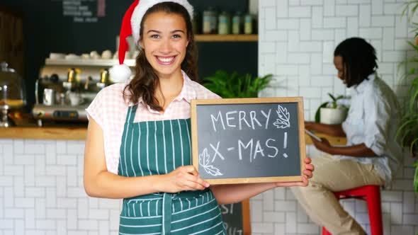 Portrait of waitress standing with merry x mas board