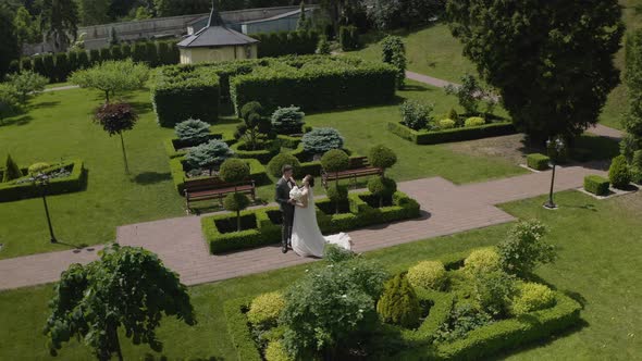 Newlyweds Caucasian Groom with Bride Walking Embracing Hugs Making a Kiss in Park Wedding Couple