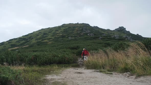 Tourist with a Backpack Goes Down Along the Stone Trail on Mountain Hill