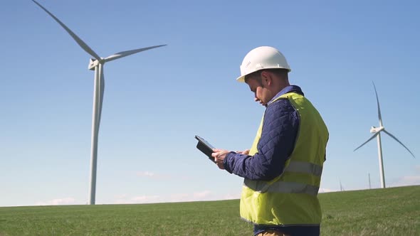 Engineer Standing Near Wind Mill and Checking Information on Dev