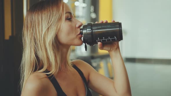 Attractive Young Sport Girl Drinking Water in a Professional Gym