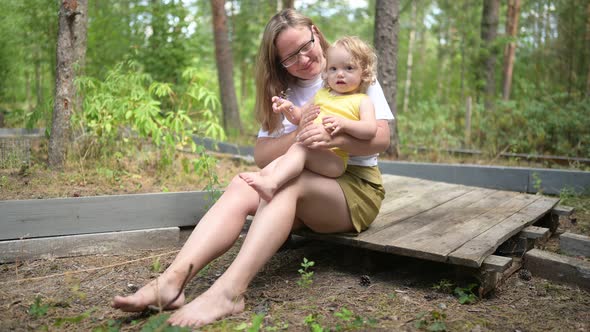 Little Cute Baby Toddler Girl Blonde with Curls on Mother's Arms