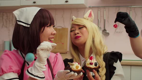 Joyful Asian Woman in Cosplay Costume Feeding Cherry Candy to Girlfriend