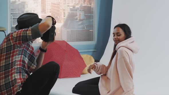 Close-up of Make-up Artist Applying Makeup on Beautiful Black Model Sitting on the Floor and Posing