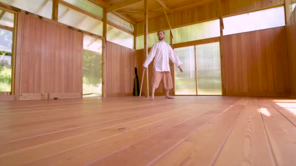 A Caucasian Bearded Man with Long Blond Hair Practices Qigong and Taichi in a Wooden Practice Room