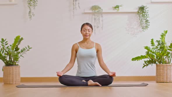 Calm of wellness Asian young woman sit on yoga mat doing breathing with yoga lotus pose.Yoga meditat