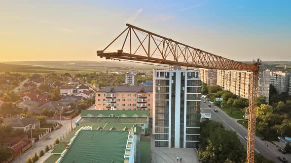 Aerial drone view of a construction crane in Balti, Moldova at sunset. Road with cars, residential b