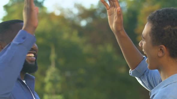 Cheerful Black Dad and Son Giving High-Five, Man Congratulating Son, Achievement