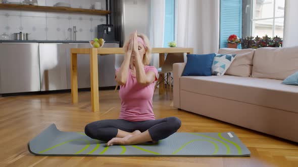 Mature Female Meditating in Lotus Pose at Home