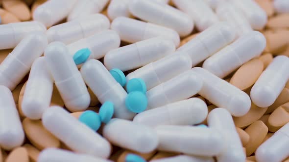 Small Round Blue Tablets Fall on White Capsules with Painkillers Orange Pills.