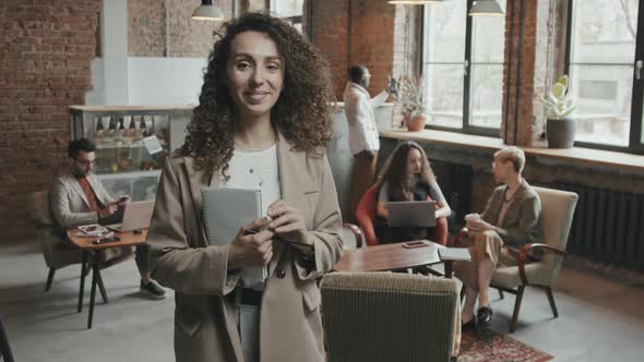 Young Businesswoman Posing for Camera with Notebook in Hands