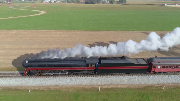 Aerial Side View of a Restored Steam Engine Blowing Steam and Smoke