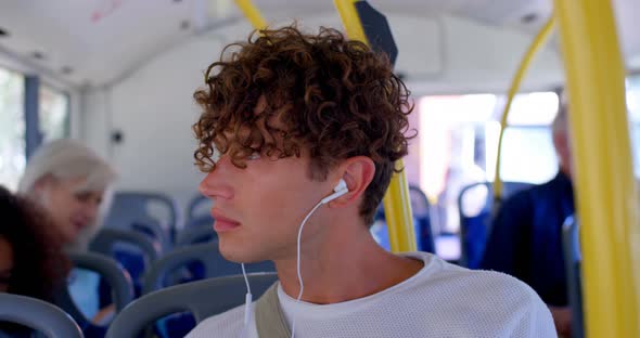 Male commuter listening music on earphones while travelling in bus 4k