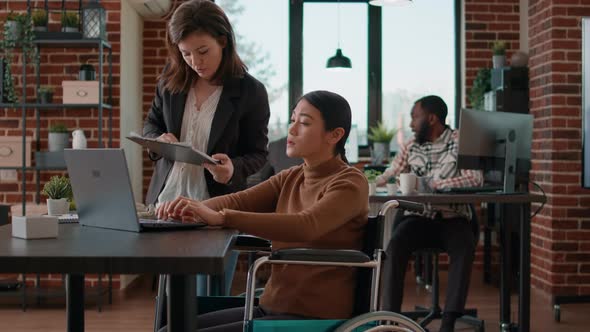 Asian Woman in Wheelchair Brainstorming Ideas with Colleague