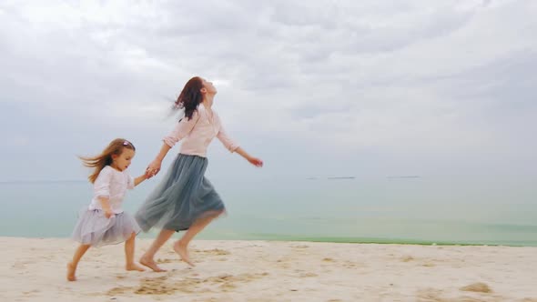 Mom and Daughter Having Fun, Running Around on the Beach. Happy Childhood