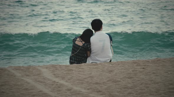 Unrecognizable asian couple hugging on coastline