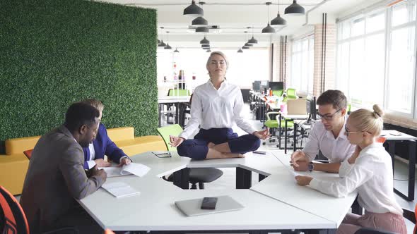 Young Caucasian Woman Meditating in Office While Colleagues Are Working Keep Calm Meditate