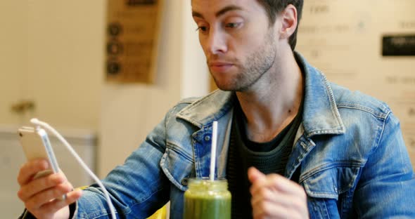Man using mobile phone while drinking juice