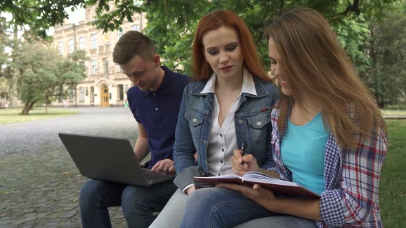 Female Student Writes in Her Exercise Book on Campus