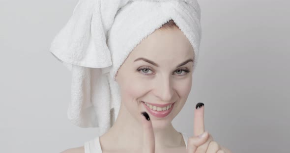 Gorgeous Woman with Towel on Her Head Applying Purifying Black Charcoal Mask on Her Face