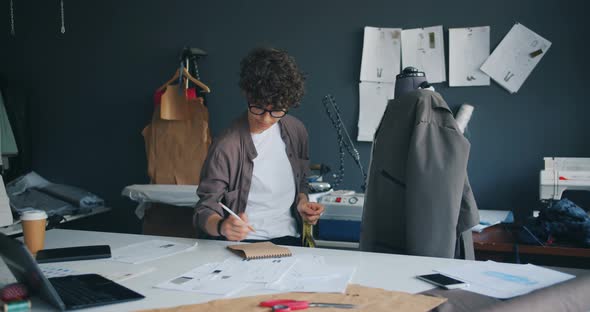 Young Woman Clothes Designer Measuring Coat with Measure-tape Writing Notes