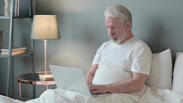Old Man with Laptop Coughing in Bed