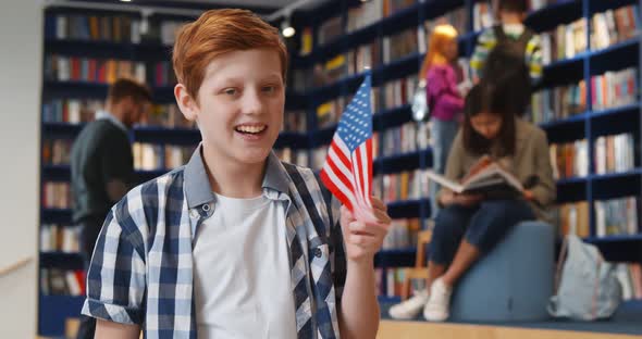 Portrait of Preteen Boy Holding American Flag Standing in Public School Library
