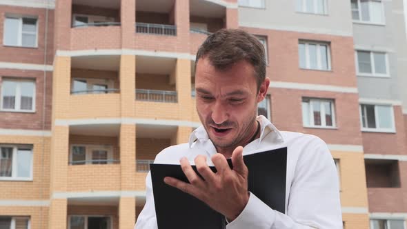 Closeup of a Joyful Businessman in a White Shirt Making Notes in a Notebook