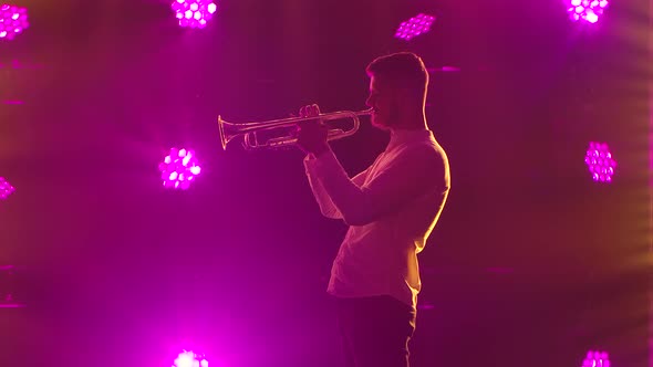 A Side View of a Professional Trumpet Player. Shot in a Smoky Dark Studio with Dynamic Multicolored