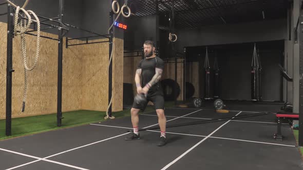 Brutal Strong Man Using Kettlebell Weights Doing Exercise in the Fitness Center of Gym