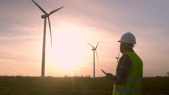 Windmill Engineer Watching Wind Turbines in Operation on a Tablet