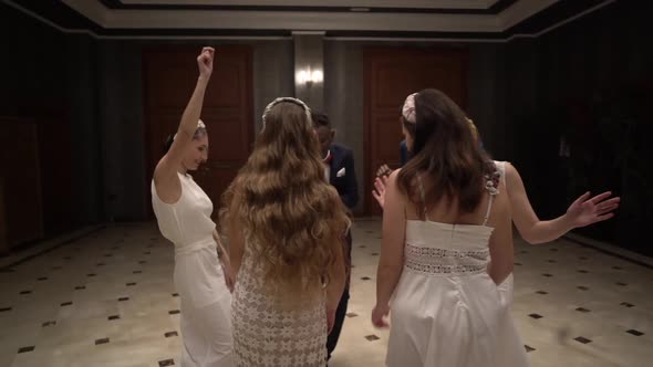 Carefree guests and newlyweds dancing in hall together